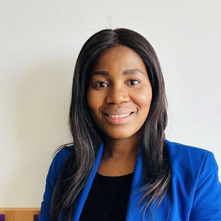 Professional woman in blue blazer smiling, inspiring futures through learning.